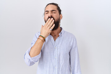 Hispanic man with beard wearing casual shirt bored yawning tired covering mouth with hand. restless...