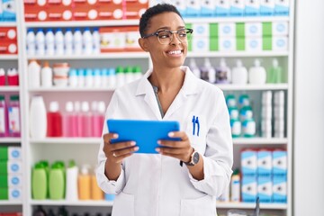African american woman pharmacist using touchpad working at pharmacy