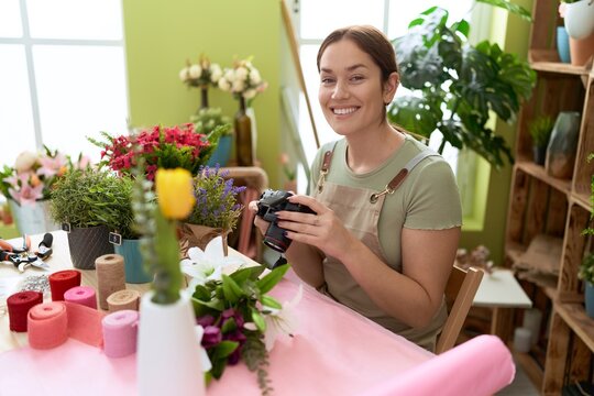 Young beautiful woman florist make photo to bouquet of flowers at flower shop
