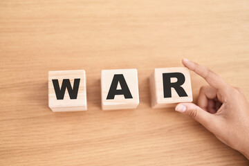 Woman hand holding cubes with war word on the table
