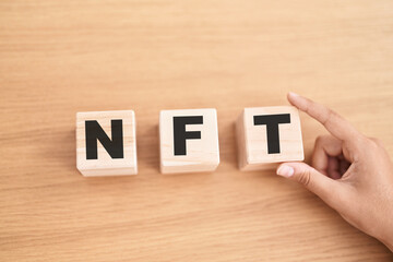 Woman hand holding cubes with nft word on the table