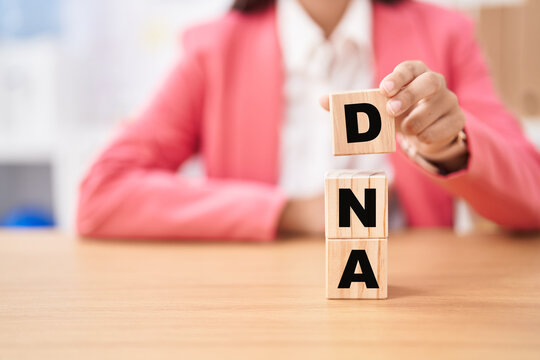 Business woman holding cubes with dna word on the table
