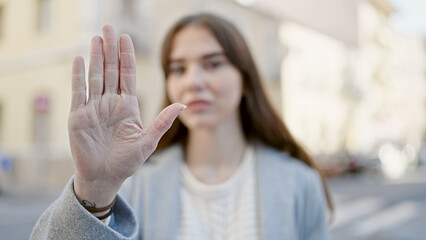 Young hispanic woman doing stop gesture with hand at street