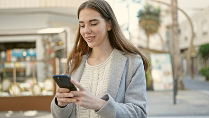 Fototapeta premium Young hispanic woman using smartphone smiling at coffee shop terrace