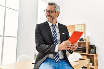 Middle age grey-haired man architect smiling confident using touchpad at office