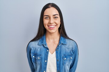 Hispanic woman standing over blue background with a happy and cool smile on face. lucky person. - obrazy, fototapety, plakaty