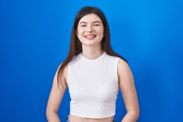 Fototapeta na wymiar Young caucasian woman standing over blue background with a happy and cool smile on face. lucky person.