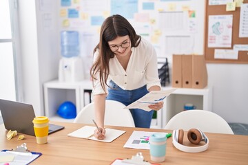 Young caucasian woman business worker writing on document at office