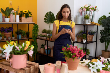 Young african american woman florist using smartphone at flower shop