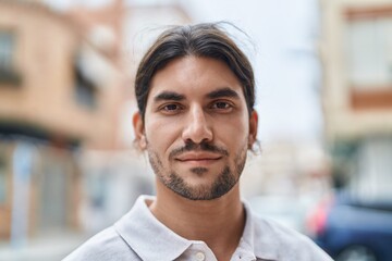 Obraz premium Young hispanic man with relaxed expression standing at street