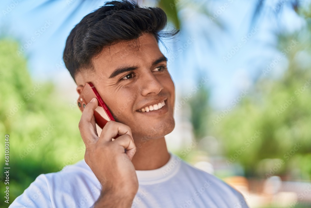 Poster Young hispanic man smiling confident talking on the smartphone at park