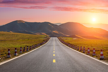Straight asphalt highway road and mountain natural landscape at sunset