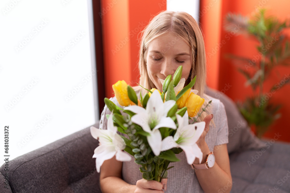 Poster Young blonde woman surprise with bouquet of flowers sitting on sofa at home