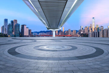 Round city square and skyline with modern buildings at sunset in Chongqing, China. Empty square floor and bridge with skyline background.