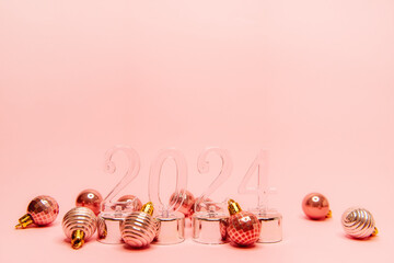 On an isolated soft pink background transparent numbers 2024 with shiny Christmas balls. New Year...
