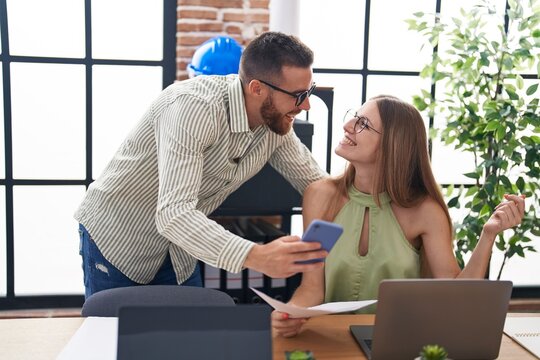 Man and woman business workers using laptop and smartphone at office