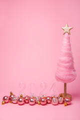 Isolated bright pink background fluffy creative Christmas tree made of wool, transparent numbers 2024 with shiny balls. New Year holiday card. Template for text. Cotton candy, online sales, shopping