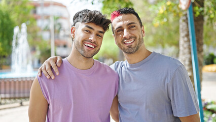 Naklejka premium Two men couple smiling confident hugging each other at park