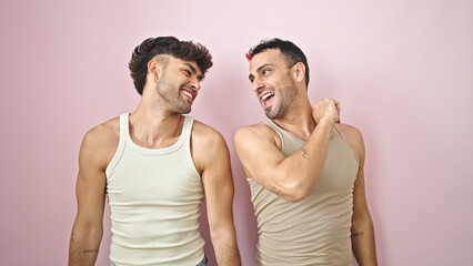 Two men couple smiling confident standing together over isolated pink background