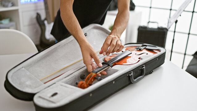 Passionate hispanic musician's hands gently opening violin case at cozy music studio
