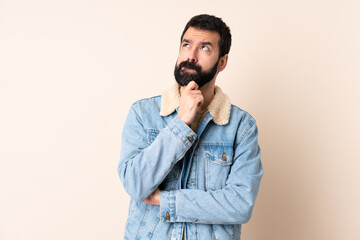 Caucasian man with beard over isolated background having doubts and thinking