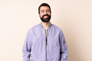 Caucasian man with beard wearing a jacket over isolated background laughing