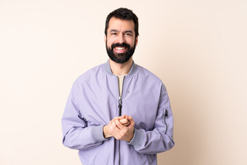 Caucasian man with beard wearing a jacket over isolated background laughing