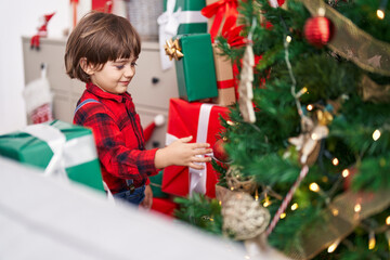 Adorable toddler smiling confident decorating christmas tree at home