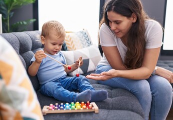 Mother and son sitting on sofa playing xylophone at home