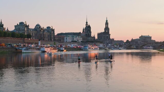 The beautiful city of Dresden at the golden hour, paddle steamers are on the quay and people paddle on the Elbe.