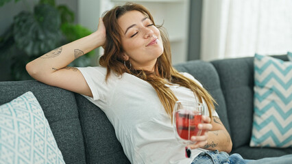 Young beautiful hispanic woman drinking tea relaxed on sofa at home