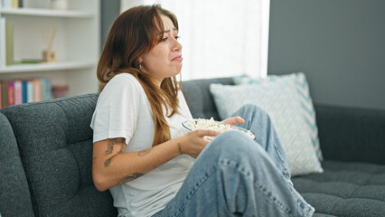 Obraz premium Young beautiful hispanic woman watching drama movie crying at home