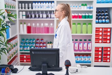 Young caucasian woman working at pharmacy drugstore looking to side, relax profile pose with...