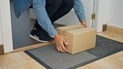 Young beautiful hispanic woman opening door holding package at home