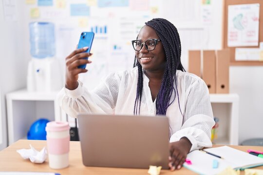 African american woman business worker using laptop make selfie by smartphone at office