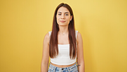 Obraz premium Young beautiful hispanic woman standing with serious expression over isolated yellow background