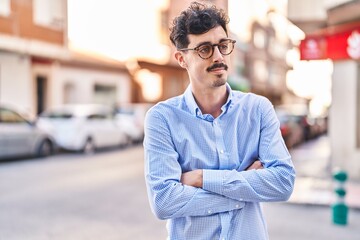 Young caucasian man standing with arms crossed gesture at street