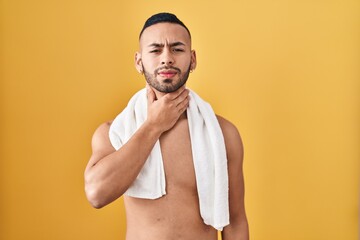 Fototapeta premium Young hispanic man standing shirtless with towel touching painful neck, sore throat for flu, clod and infection