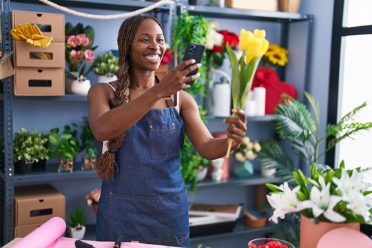 African american woman florist make photo to flower by smartphone at flower shop