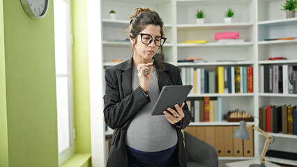 Young pregnant woman teacher using touchpad at library university