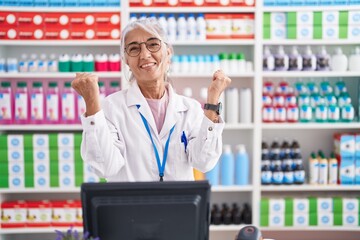 Middle age woman with tattoos working at pharmacy drugstore celebrating surprised and amazed for...