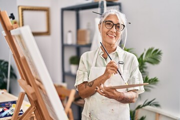 Middle age grey-haired woman artist smiling confident drawing at art studio