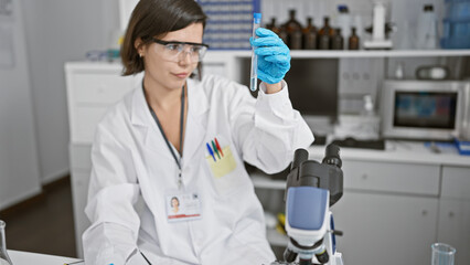 Naklejka premium Young beautiful hispanic woman scientist holding test tube at laboratory