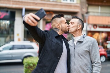 Two men couple make selfie by smartphone kissing at street