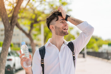 Young handsome man with a bottle of water at outdoors has realized something and intending the...