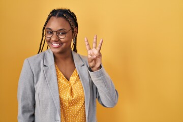 African american woman with braids standing over yellow background showing and pointing up with...