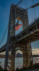 Low angle view of  a huge American Flag hanging from the west tower of the George Washington Bridge on a sunny day.