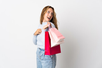 Fototapeta na wymiar Young blonde woman isolated on white background holding shopping bags and smiling