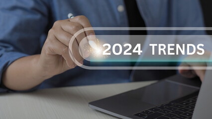 Businessman holding pen with 2024 trends searching bar for marketing monitor and business planning...