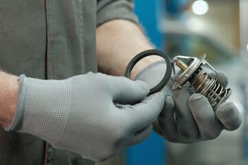 Thermostat for an automobile engine.Close-up.The car mechanic controls the quality of the new...